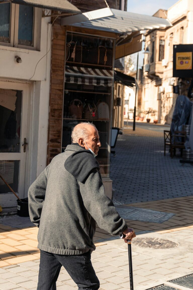 Older adult using a properly fitted walker on a clear indoor path beside a supportive chair.